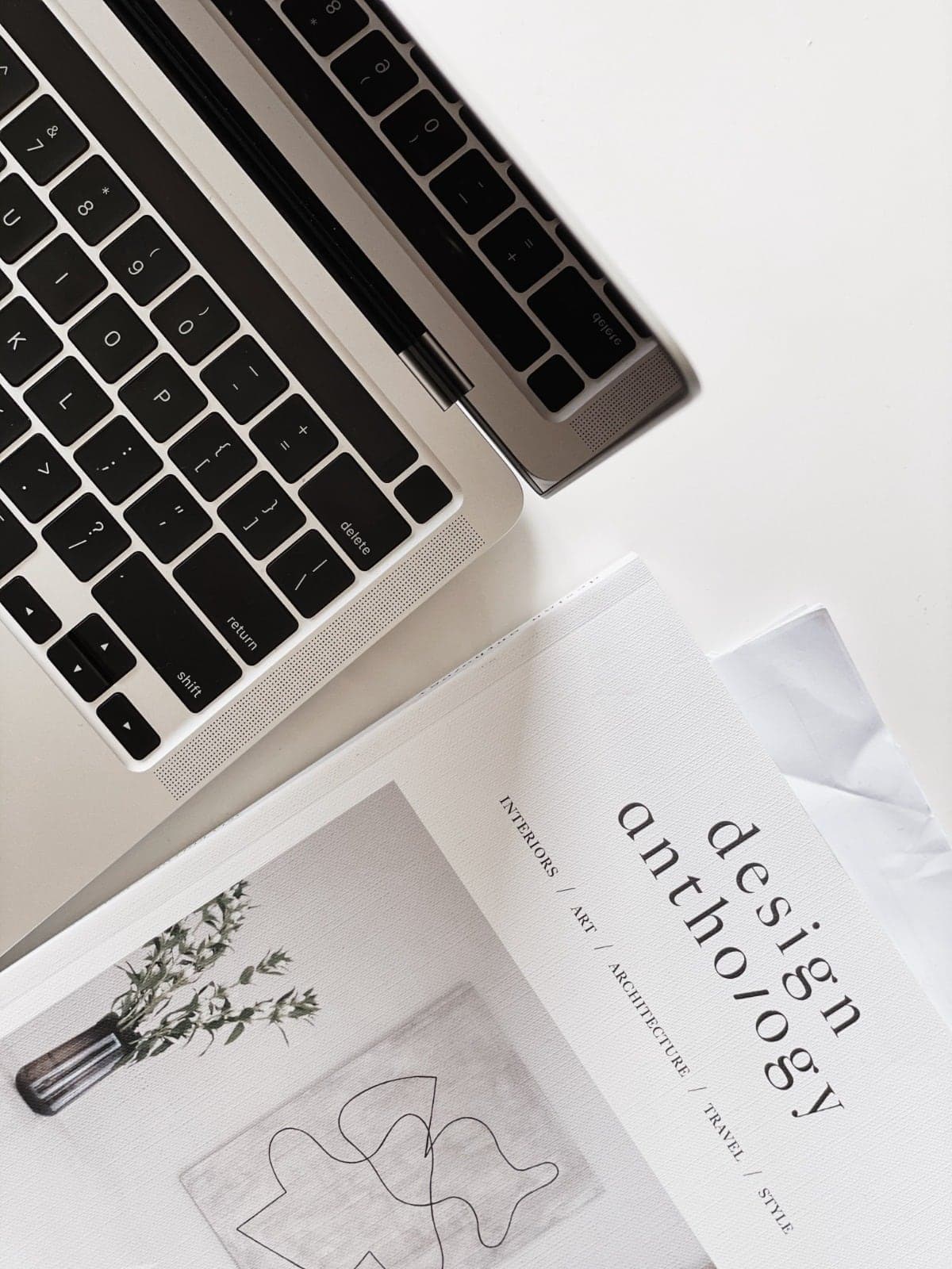 A laptop beside an open design book