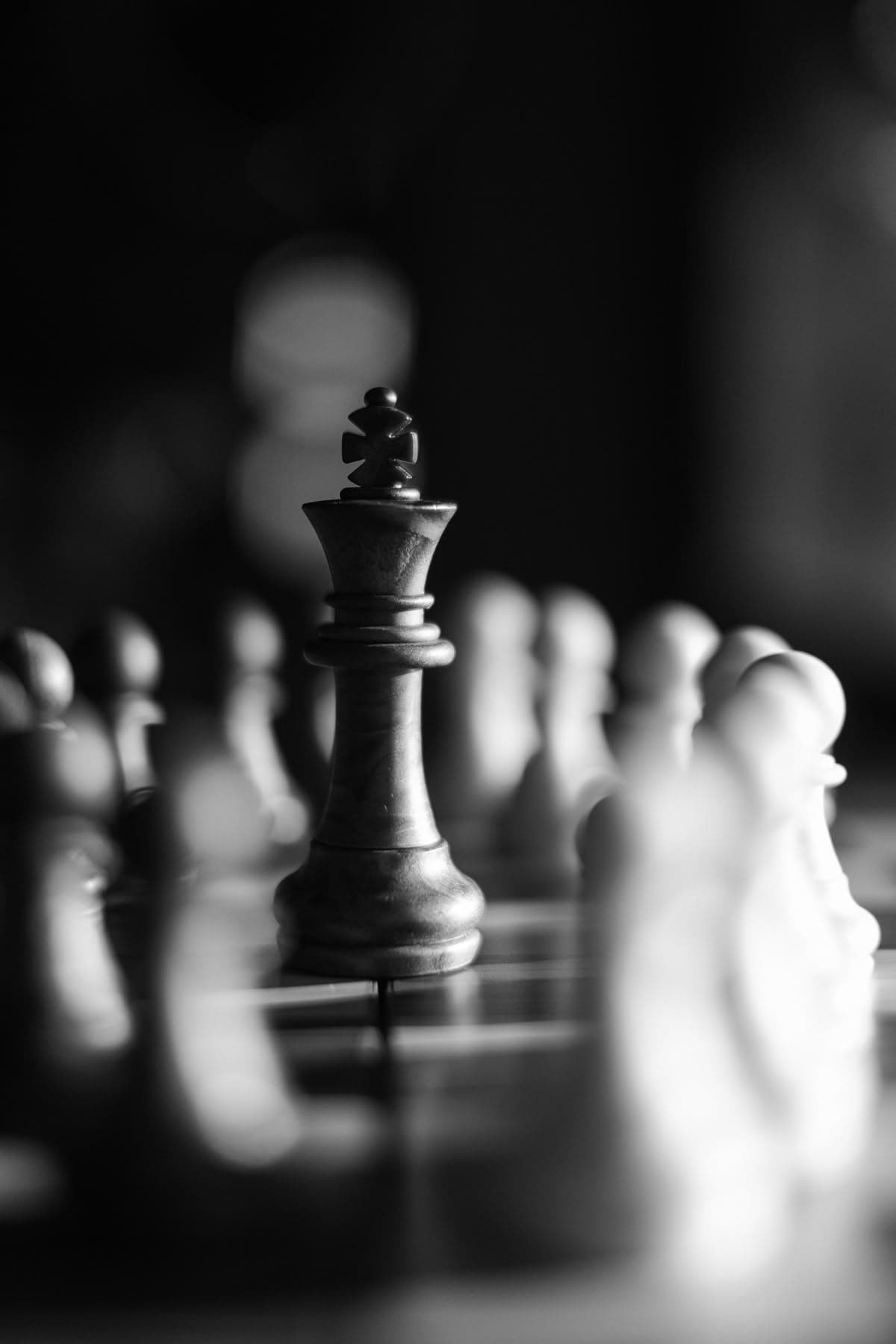 A black king standing among blurred pawns on a chessboard