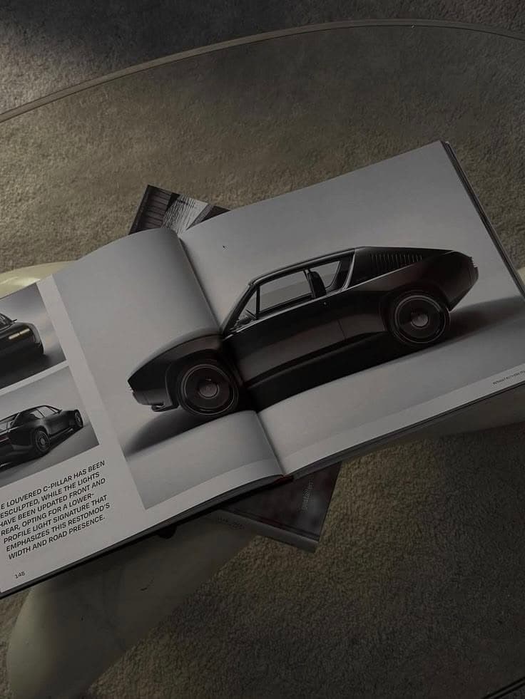 An open coffee-table book showing a dark concept car illustration